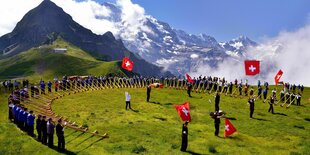 Alphornbläse stehen im Halbkreis auf der Kleinen Scheidegg im Kanton Bern