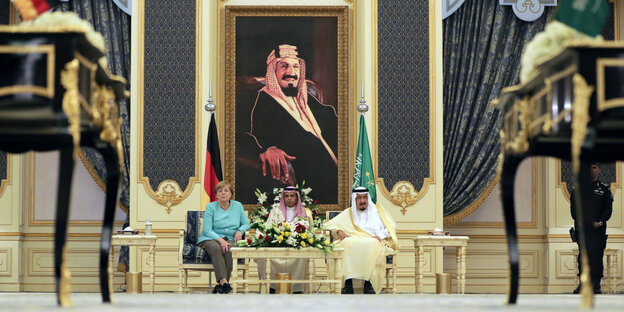 Kanzlerin Merkel sitzt neben dem König von Saudi-Arabien. Im Hintergrund ein großes Bild des Königs