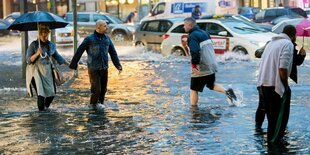 Passanten waten über eine überschwemmte Straße in Berlin