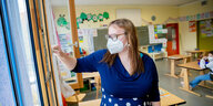 Eine Lehrerin steht in einem Klassenzimmer mit Maske