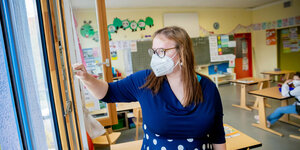 Eine Lehrerin steht in einem Klassenzimmer mit Maske
