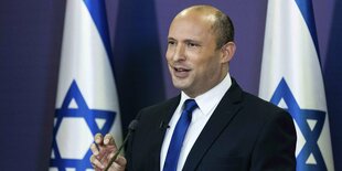 Bennett an einem Rednerpult vor israelischen Flaggen