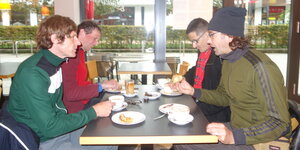 Vier Männer sitzen am Frühstückstich