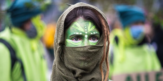 Aktivistin mit bemaltem Gesicht protestiert gegen die Rodung der Bäume für die A49