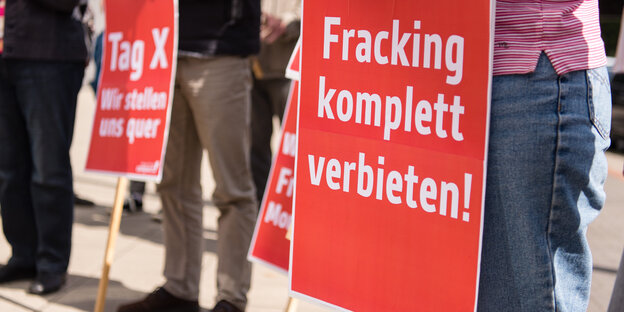 Menschen halten bei einer Demonstration Schilder hoch, auf denen steht "Fracking tötet" und "Hände weg vom Moratorium"