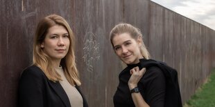 Im Vordergrund stehen zwei blonde Frauen, die