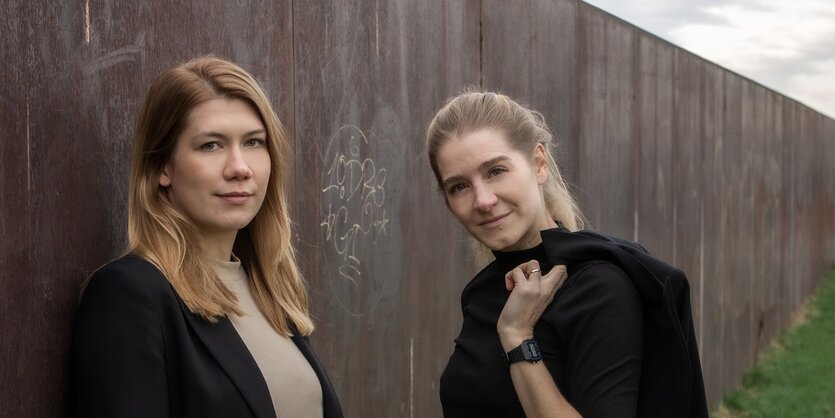 Im Vordergrund stehen zwei blonde Frauen, die