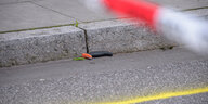 Ein Messergriff mit abgebrochener Klinge liegt am Straßenrand unter einem Absperrband