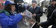 Strassenszene: eine Frau hält eine ukrainische Zeitung in der Hand