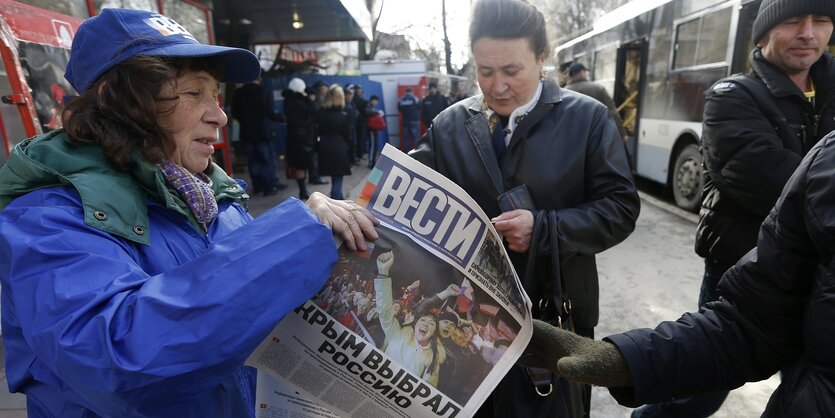 Strassenszene: eine Frau hält eine ukrainische Zeitung in der Hand