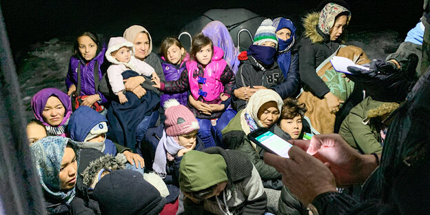 Geflüchtete Frauen und Kinder in warmer Kleidung stehen nachts zusammen