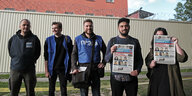 JOurnalisten stehen mit einer Zeitung vor einem Gefängnis