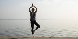 Eine Frau macht die Yogastellung Baum