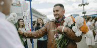 Stepan Latypow, oppositioneller Aktivist aus Belarus, bekommt bei einer Demonstration in Minsk Blumen überreicht