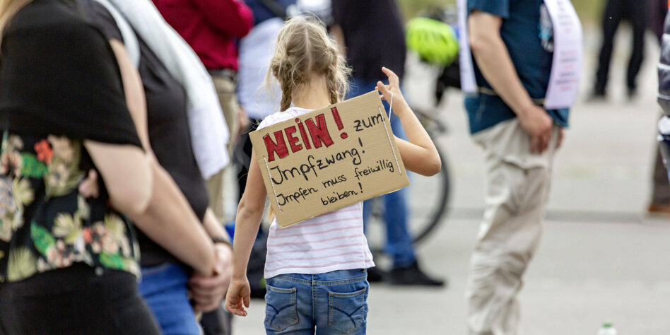 Ein Mädchen bei Querdenken-Demo trägt ein Schild mit der Aufschrift "Nein zum Impfzwang" auf dem Rücken