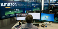 Nasdaq-Mitarbeiter überwacht die Marktaktivitäten in New York, im Hintergrund ist das Logo von Amazon zu sehen
