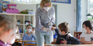 Lehrerin sammelt alle Teststreifen des Corona Lolli-Tests in einem Klassenzimmer ein