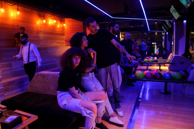 Junge Menschen aus Syrien sitzen neben einer Bowlingbahn.