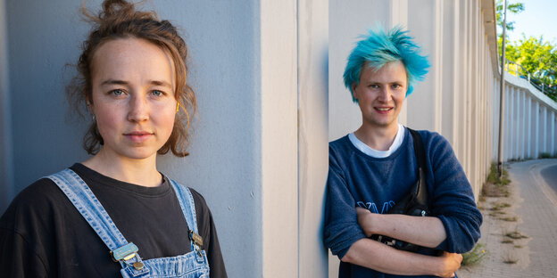 Lou Winters und Jassin Braun, AktivistInnen von Sand im Getriebe, stehen an einer Autobahnmauer in Berlin