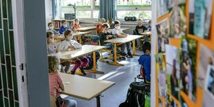 Durch eine offene Tür blickt man in ein Klassenzimmer mit Schüler/innen die Masken tragen