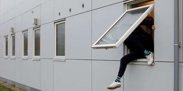 Mann klettert aus Containerbau-Fenster