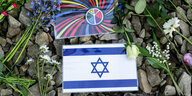 Eine Israel-Flagge und ein Friedenszeichen liegen auf Steinen