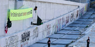 Aktivisten hängen mit einem großen Protestbanner an der Wand über Autobahntrasse. Polizisten stehen unten und schauen nach oben