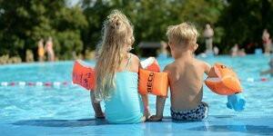 Zwei Kids sitzen am Rande eines Schwimmingspools