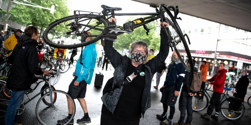 Eine Frau reckt ihr Fahrrad in die Höhe