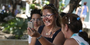 Menschen in Havanna betrachten ein Handy