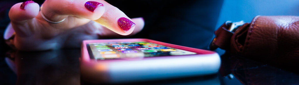 Ein Finger mit Nagellack tippt auf ein Smartphone