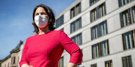 Annalena Baerbock in Kleid und Maske draußen vor einem Gebäude