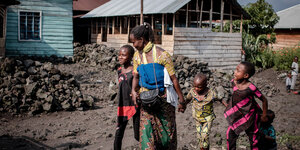 Eine Frau in traditioneller afrikan. Kleidung mit drei Kindern an der Hand