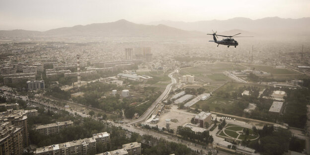 Ein Black Hawk Helikopter der US Army zeichnet sich ab vor der Stadtansicht auf Kabul