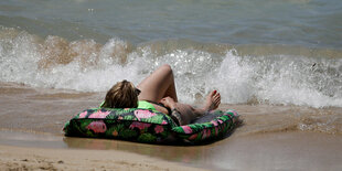 Frau mit Luftmatratze am Strand