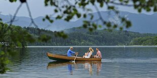 Ein Elternpaar mit ihrem Sohn und dem Großvater in einem Ruderboot - Der Großvater rudert