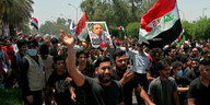 Demonstranten tragen Fahnen und ein Plakat mit dem Abbild des getöteten Aktivisten Ihab al-Wasni