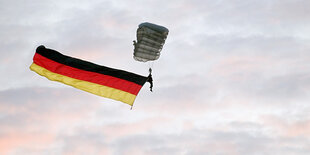 Gleitflieger und Fahne in den Farben Schwarz-Rot-Gold am Himmel