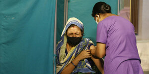 Eine ältere Frau verzieht das Gesicht als sie eine Impfung bekommt