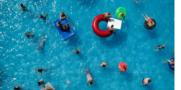 Menschen mit und ohne Schwimmreifen tummeln sich im Freibadbecken
