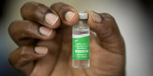 Eine Hand mit einem Fläschchen AstraZeneca Impfstoff