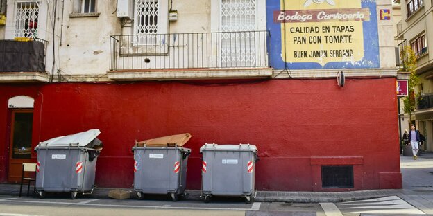Müllcontainer mit verschiedenfarbigen Deckeln zur Mülltrennung auf einer Straße in Barcelonaner leeren Gasse