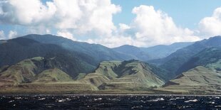 Blick vom Wasser aus auf grüne Berge