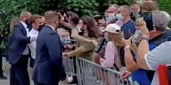 Emmanuel Macron steht hinter einer Absperrung, auf der anderen Seite viele Menschen, die mit dem Handy filmen. Er wird von einem Mann geschlagen