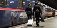 Zwei Frauen laufen auf einem Bahnsteig, dort wartet ein Nachtzug der Österreichischen Bundesbahnen