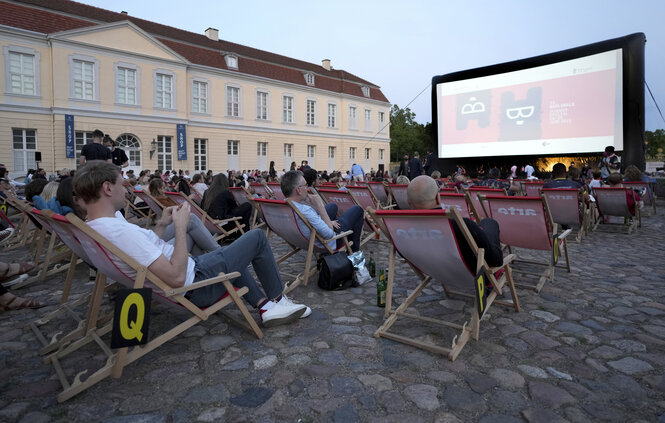 Menschen sitzen in Liegestühlen in einem Freiluftkino