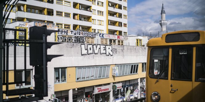 Eine U-Bahn fährt auf Hochschienen an den Häusern des Kottbusser Tores in Berlin entlang