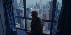 Szene aus „Wood and Water“, Frau vor der Skyline Hong Kongs