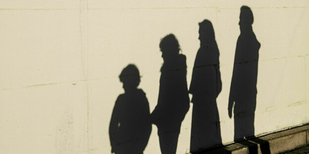 Schatten von vier Personen auf einer Wand.