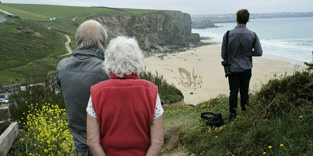 Menschen blicken von einer Klippe auf den Strand in Newqay, Cornwall